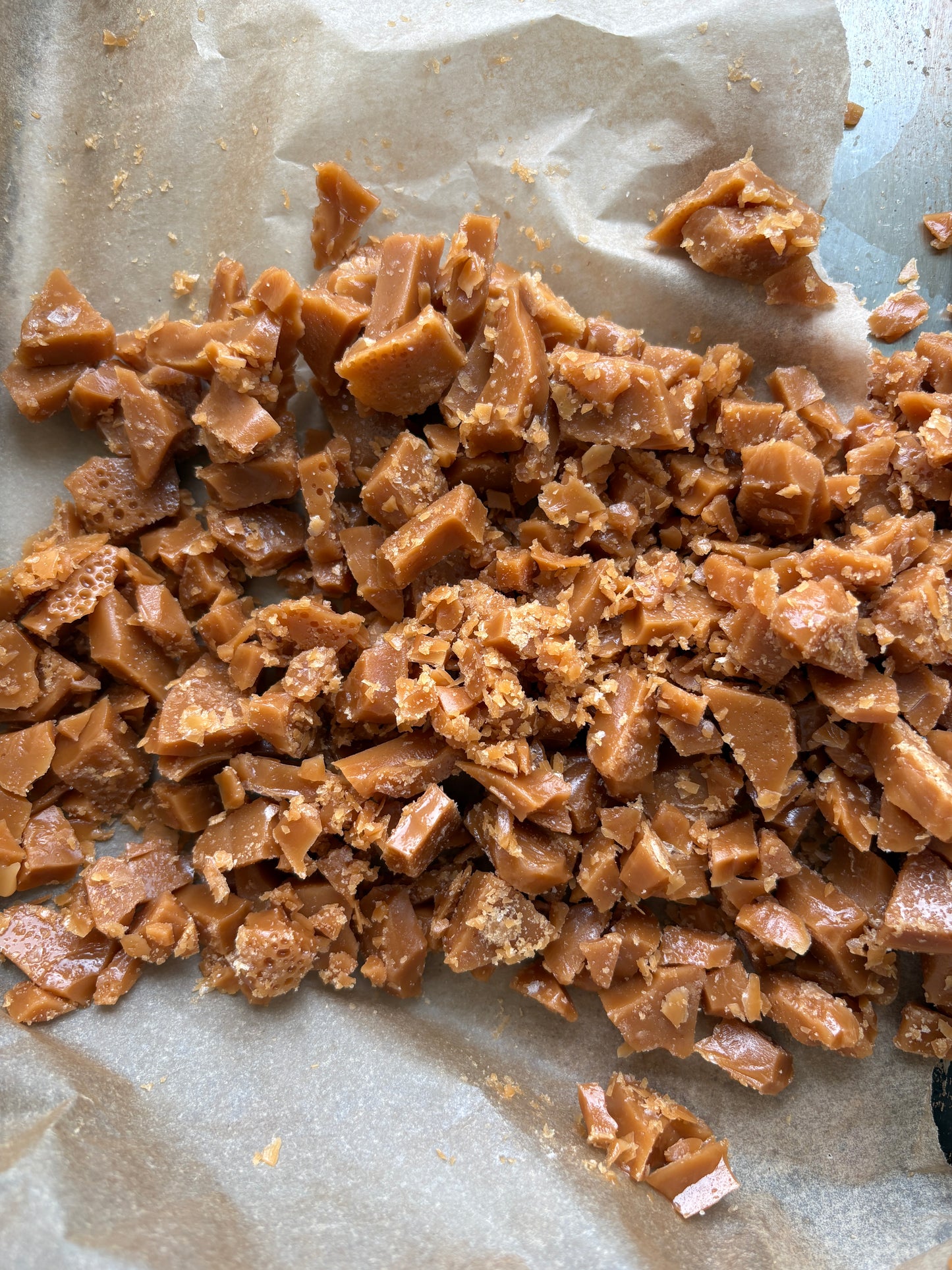 Chipped salted caramel pieces scattered on a sheet of light brown parchment paper.