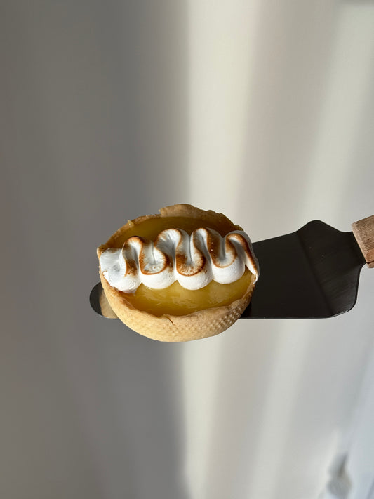 A close-up of a gluten free tart shell filled with a lemon curd filling and topped with torched meringue.