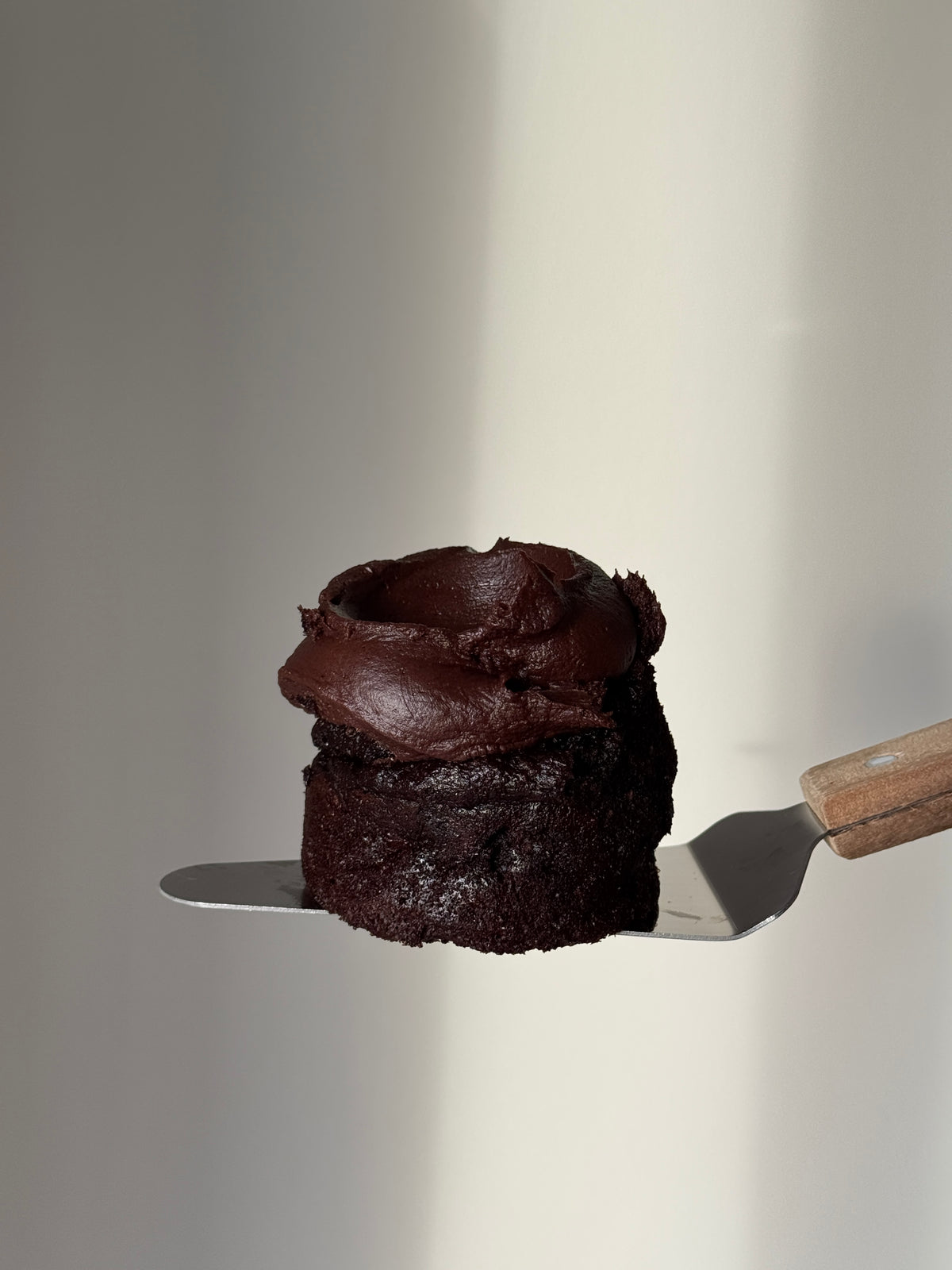 A mini round gluten free chocolate cake topped with chocolate frosting