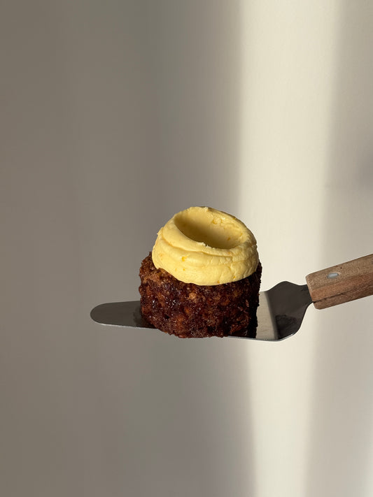 A mini round gluten free Carrot Cake topped with orange flavoured frosting